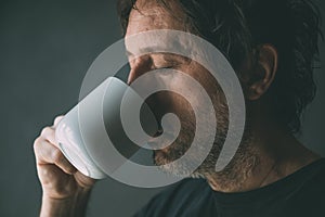 Unkempt man drinking morning coffee from a white mug