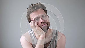 Unkempt man in glasses having headache after party. Being stressed or ill.