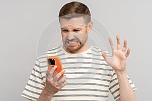 Unkind guy angry looks screen smartphone, aggressive video call, twisting face, making evil grimace.