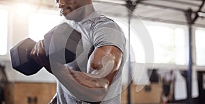 Unknown african american athlete lifting dumbbell during bicep curl arm workout in gym. Strong, fit, active black man