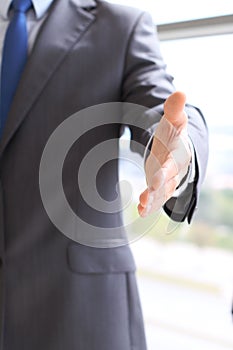 Unknown business man offering handshake while standing straight. Success cooperation and agreement concepts