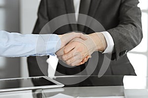 Unknown business man and woman are shaking hands finishing contract signing, close-up. Business and handshake concept