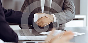 Unknown business people are shaking hands after contract signing in modern office, close-up. Handshake as successful