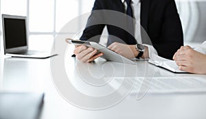 Unknown business people using tablet computer in modern office. Businessman or male entrepreneur is working with his