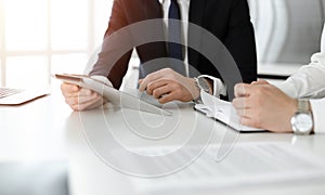 Unknown business people using tablet computer in sunny office. Businessman is working with his colleague at the desk