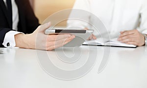 Unknown business people using tablet computer in sunny office. Businessman is working with his colleague at the desk