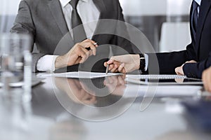 Unknown business people working together at meeting in modern office, close-up. Businessman and woman with colleagues or