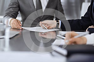 Unknown business people working together at meeting in modern office, close-up. Businessman and woman with colleagues or