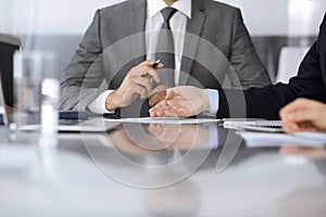 Unknown business people working together at meeting in modern office, close-up. Businessman and woman with colleagues or