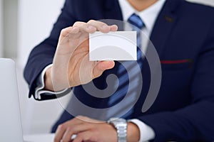 Unknown businessman or lawyer giving a business card while sitting at the table, close-up. He offering partnership an