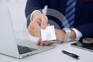 Unknown businessman or lawyer giving a business card while sitting at the table, close-up. He offering partnership an