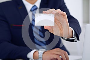 Unknown businessman or lawyer giving a business card while sitting at the table, close-up. He offering partnership an