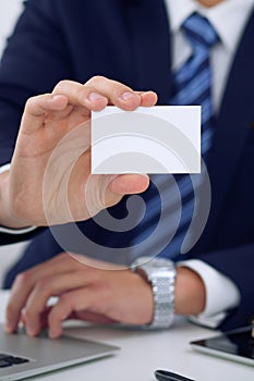 Unknown businessman or lawyer giving a business card while sitting at the table, close-up. He offering partnership an