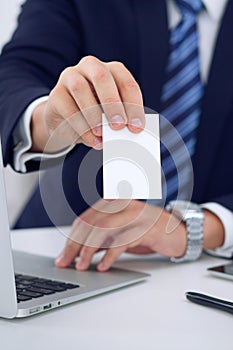 Unknown businessman or lawyer giving a business card while sitting at the table, close-up. He offering partnership an