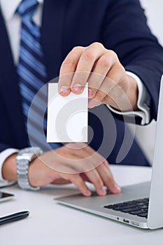 Unknown businessman or lawyer giving a business card while sitting at the table, close-up. He offering partnership an