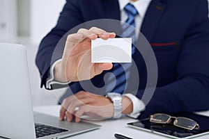 Unknown businessman or lawyer giving a business card while sitting at the table, close-up. He offering partnership an