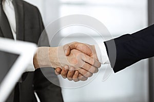 Unknown diverse business people are shaking hands finishing contract signing, close-up. Business and handshake concept