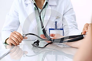 Unknown doctor woman checking blood pressure of female patient, close-up. Cardiology in medicine and health care concept