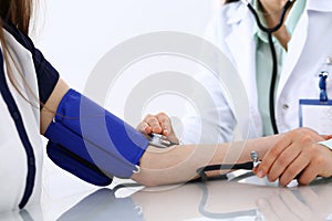Unknown doctor woman checking blood pressure of female patient, close-up. Cardiology in medicine and health care concept