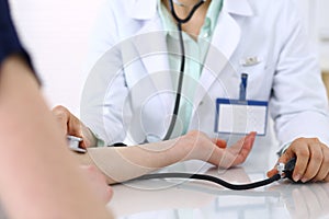 Unknown doctor woman checking blood pressure of female patient, close-up. Cardiology in medicine and health care concept