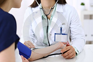 Unknown doctor woman checking blood pressure of female patient, close-up. Cardiology in medicine and health care concept