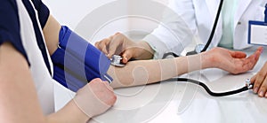 Unknown doctor woman checking blood pressure of female patient, close-up. Cardiology in medicine and health care concept