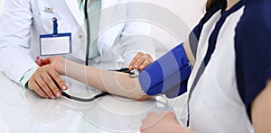 Unknown doctor woman checking blood pressure of female patient, close-up. Cardiology in medicine and health care concept