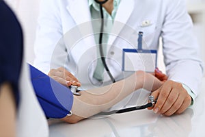 Unknown doctor woman checking blood pressure of female patient, close-up. Cardiology in medicine and health care concept