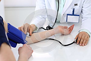 Unknown doctor woman checking blood pressure of female patient, close-up. Cardiology in medicine and health care concept