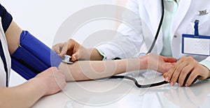 Unknown doctor woman checking blood pressure of female patient, close-up. Cardiology in medicine and health care concept