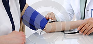 Unknown doctor woman checking blood pressure of female patient, close-up. Cardiology in medicine and health care concept