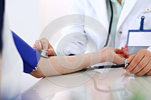 Unknown doctor woman checking blood pressure of female patient, close-up. Cardiology in medicine and health care concept photo