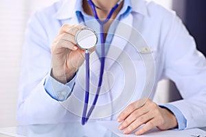 Unknown doctor woman holds stethoscope head, close-up. Physician ready to examine and help patient. Helping and