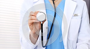 Unknown doctor woman holds stethoscope head, close-up. Physician ready to examine and help patient. Helping and