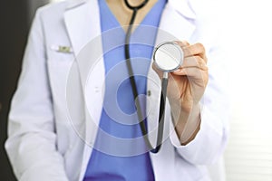 Unknown doctor woman holds stethoscope head, close-up. Physician ready to examine and help patient. Helping and