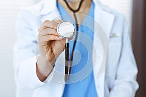 Unknown doctor woman holds stethoscope head, close-up. Physician ready to examine and help patient. Helping and