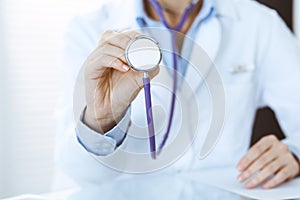 Unknown doctor woman holds stethoscope head, close-up. Physician ready to examine and help patient. Helping and