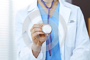 Unknown doctor woman holds stethoscope head, close-up. Physician ready to examine and help patient. Helping and