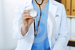 Unknown doctor woman holds stethoscope head, close-up. Physician ready to examine and help patient. Helping and