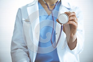 Unknown doctor woman holds stethoscope head, close-up. Physician ready to examine and help patient. Helping and