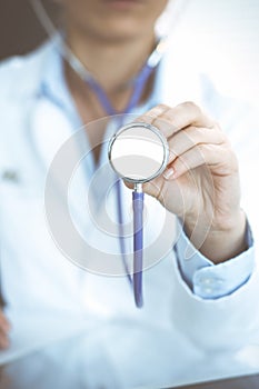 Unknown doctor woman holds stethoscope head, close-up. Physician ready to examine and help patient. Helping and