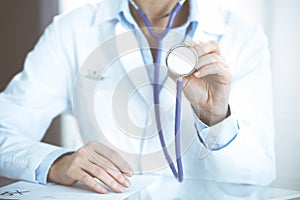 Unknown doctor woman holds stethoscope head, close-up. Physician ready to examine and help patient. Helping and