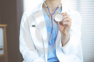 Unknown doctor woman holds stethoscope head, close-up. Physician ready to examine and help patient. Helping and