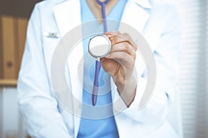 Unknown doctor woman holds stethoscope head, close-up. Physician ready to examine and help patient. Helping and