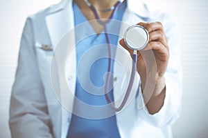 Unknown doctor woman holds stethoscope head, close-up. Physician ready to examine and help patient. Helping and