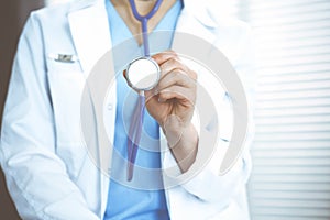 Unknown doctor woman holds stethoscope head, close-up. Physician ready to examine and help patient. Helping and