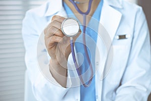 Unknown doctor woman holds stethoscope head, close-up. Physician ready to examine and help patient. Helping and