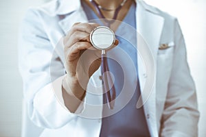 Unknown doctor woman holds stethoscope head, close-up. Physician ready to examine and help patient. Helping and