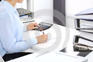 Unknown female bookkeeper or financial inspector calculating or checking balance, making report, close-up. Internal