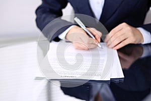 Unknown female hands with pen over document of contract. Agreement signing or business concept